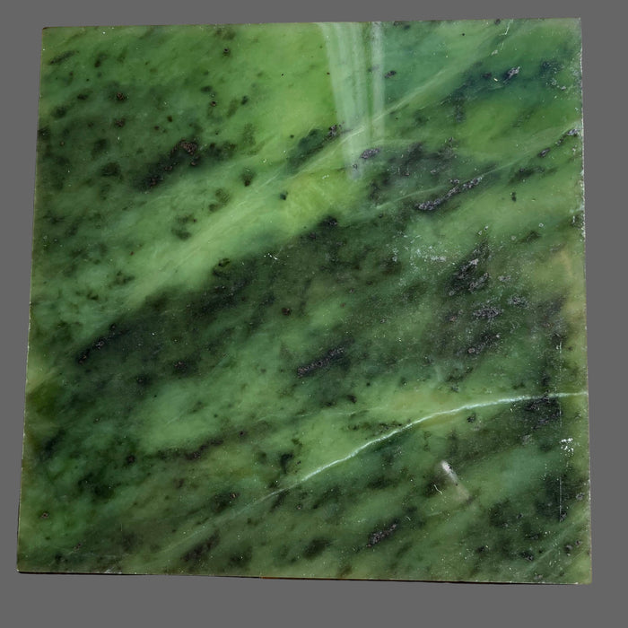Close-up of a green jade with black spots on a wooden surface
