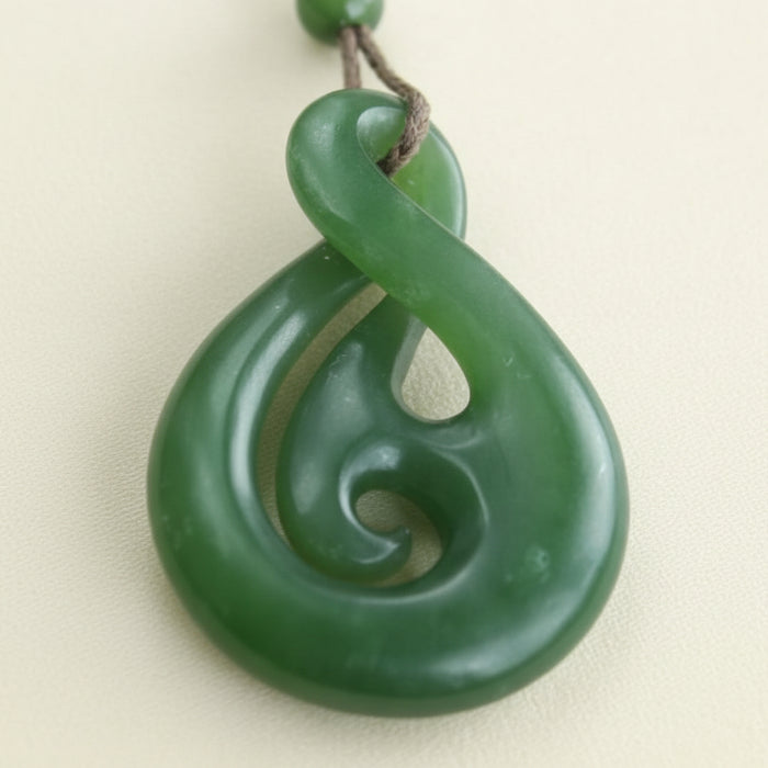 Green jade spiral pendant on a dark brown background