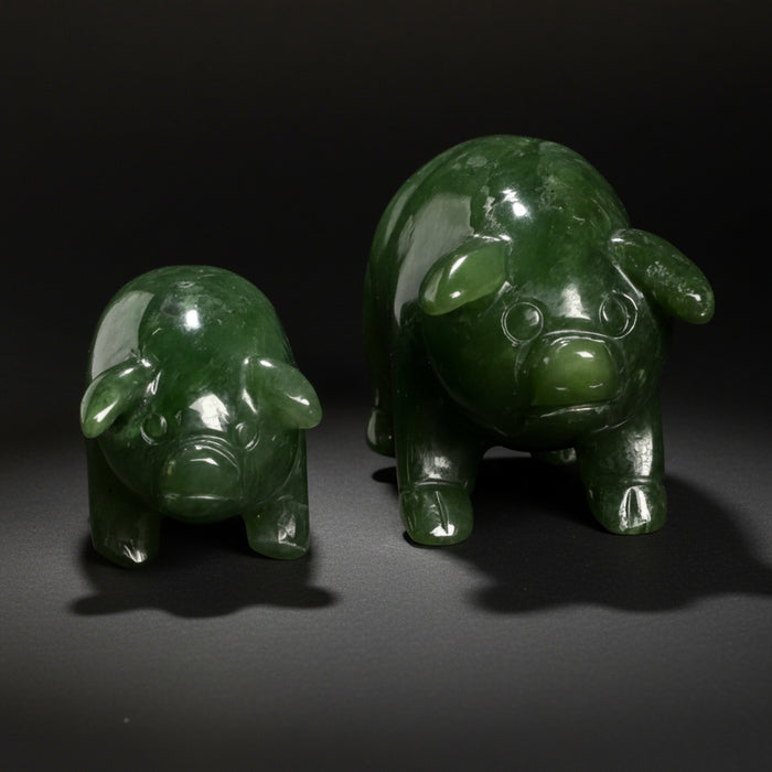 Two green pig figurines on a wooden surface with a ceramic vase in the background.