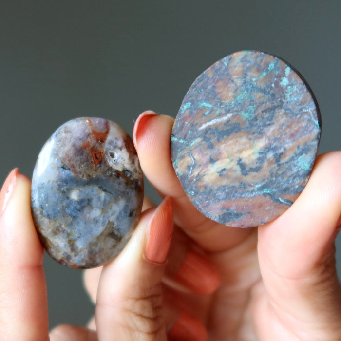 Two marbled stones held by a hand against a dark background