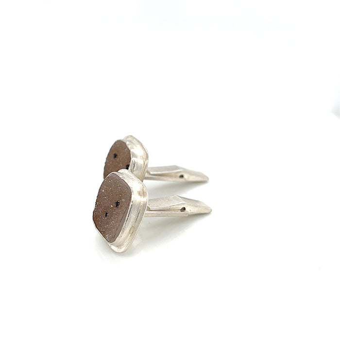 Close-up of natural quartz crystal, druzy texture, with brown inclusions, gemstone, with sterling silver cufflinks on a white background, right side close up overview.