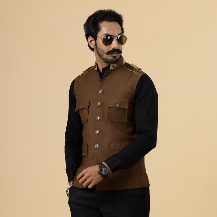 A man wearing an almond brown semi-hunting Rajputana jacket with a mandarin collar, paired with black trousers and sunglasses.