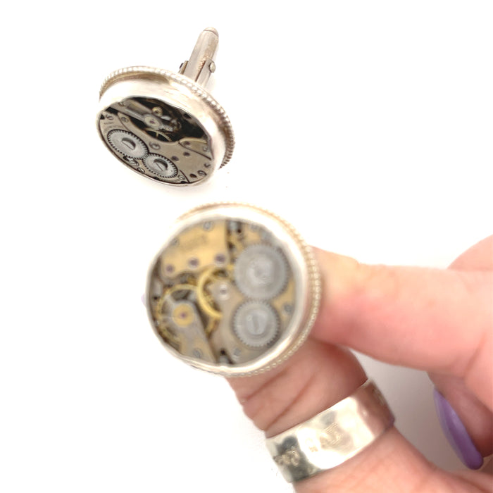 Sterling silver cuff links with mechanical detail handcrafted  in Boston on a white background in a models finger tips for a close up view.