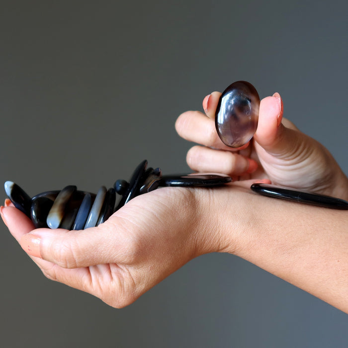 Hand holding a collection of stones against a gray background