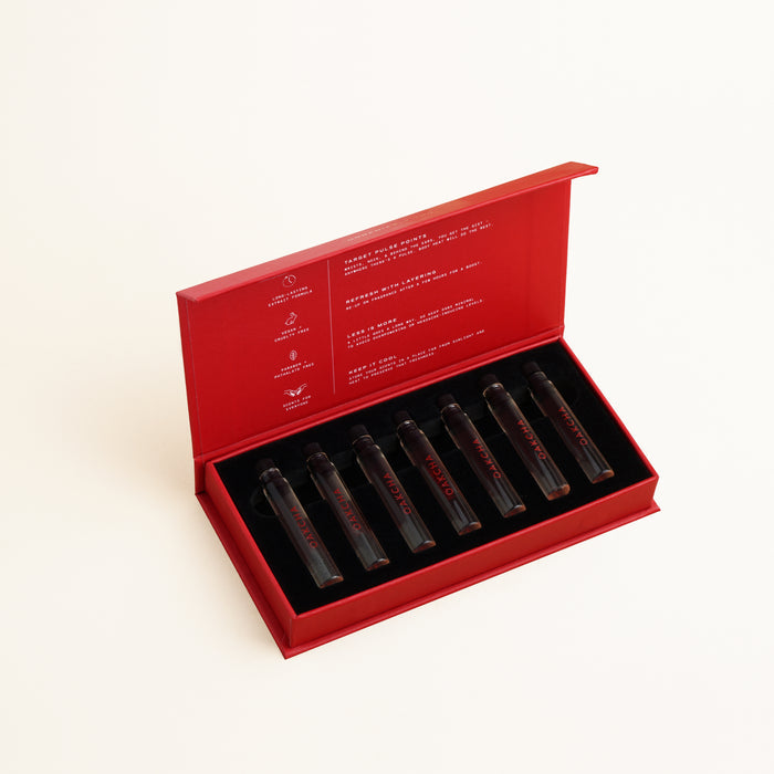 Angled view of Oakcha Discovery Sample Set open red box showing seven glass sample vials in black foam on cream background