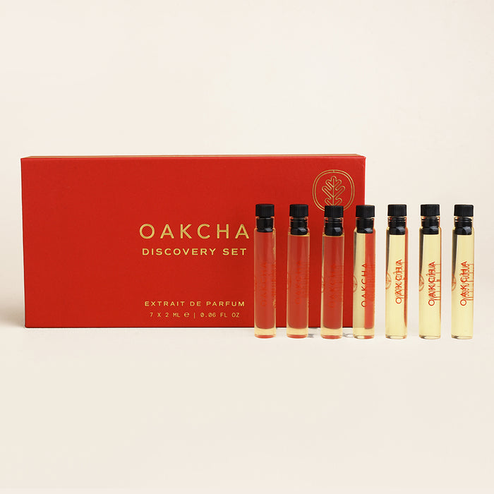 Front view of Discovery Sample Set showcasing seven 2 ml extrait de parfum vials next to a red Oakcha box on a light beige background