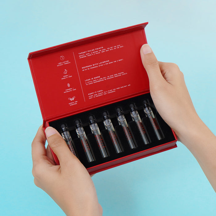 Angled view of Discovery Sample Set showing seven 2 ml extrait de parfum vials in an open red box held by hands