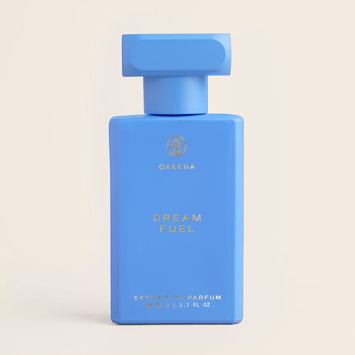 Front view of Dream Fuel 50 ml Extrait de Parfum bottle showcasing a blue rectangular design and T-shaped cap on a beige background