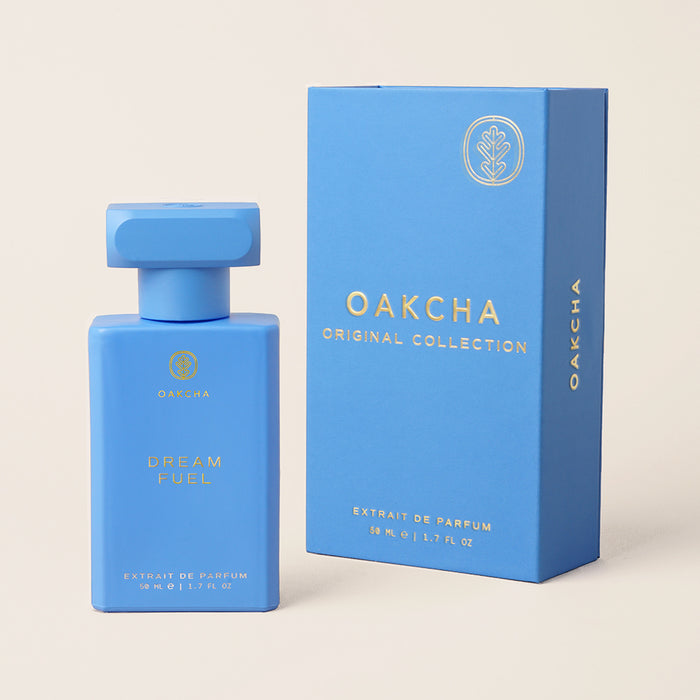 Front view of Dream Fuel 50ml perfume bottle showcasing rectangular matte blue bottle with matching box on beige background