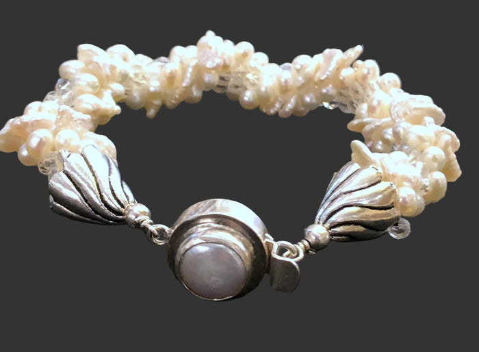 A crocheted bracelet with a combination of pearl and rock crystal beads, featuring a sterling silver pearl box clasp, displayed against a dark background.