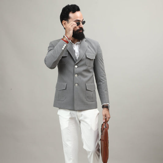 Person wearing a gray coat and white pants standing against a plain background