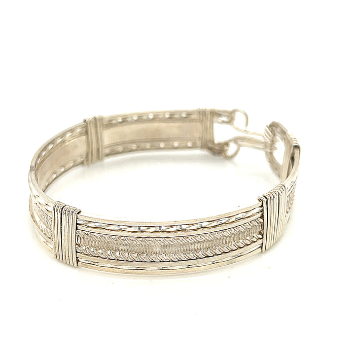 Style #1 Handcrafted sterling silver wire-wrapped bangle with twisted and straight wire combination showing polished dome centerpiece, on a white background, front left angle view.