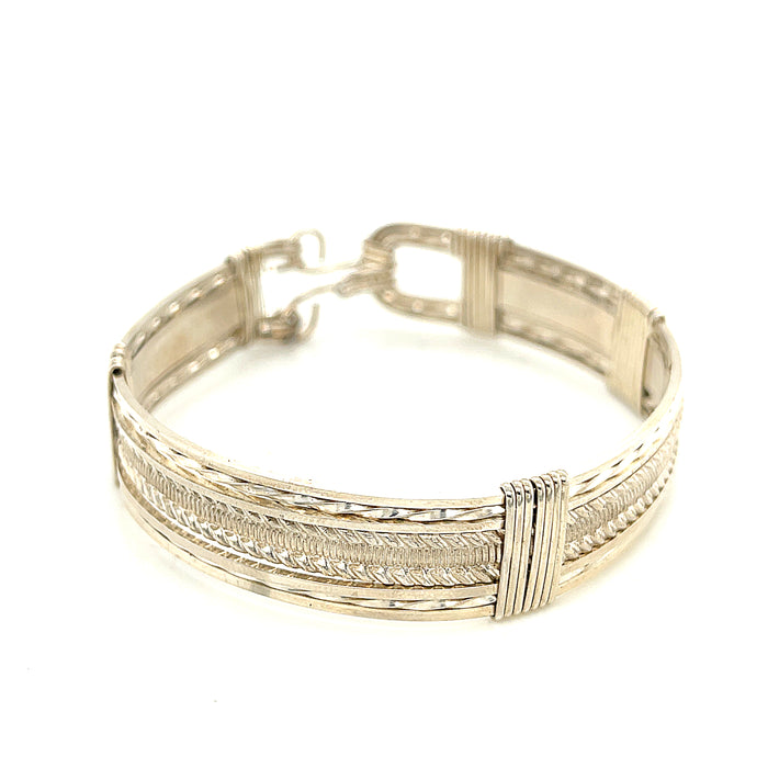 Style #1 Handcrafted sterling silver wire-wrapped bangle with twisted and straight wire combination showing polished dome centerpiece, on a white background, front close up view.