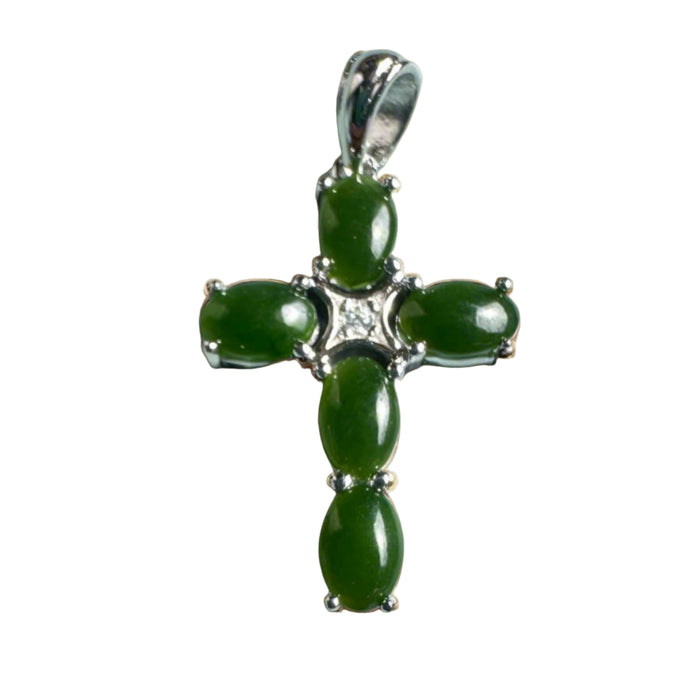 Green jade cross pendant with silver accents on a beige background