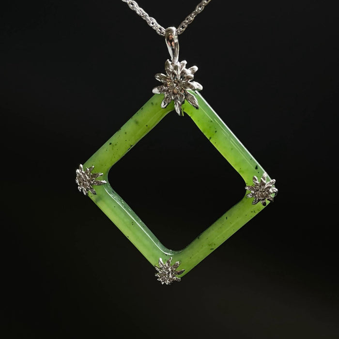 Green square jade pendant with floral elements on a black background