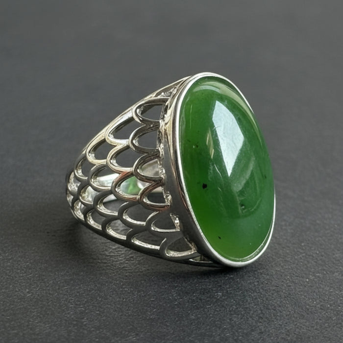 Silver ring with a green jade stone on a wooden surface with eucalyptus leaves in the background