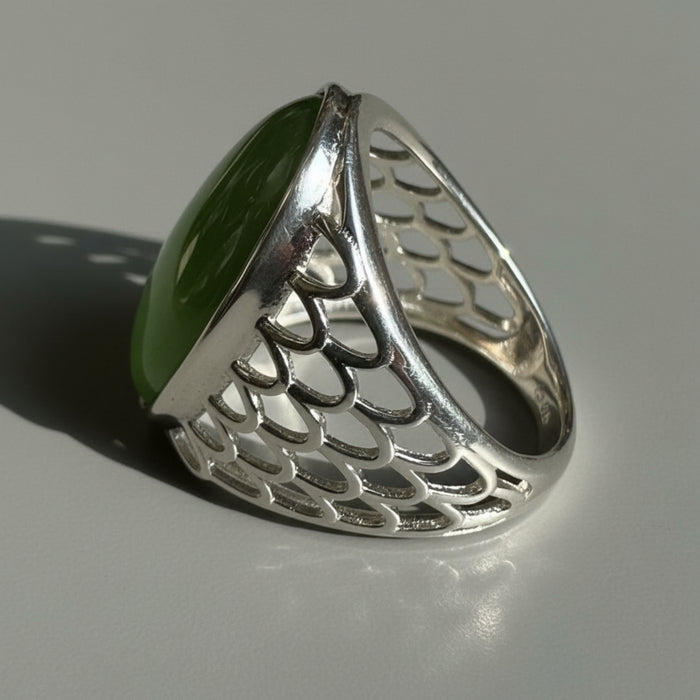 Silver ring with a green jade on a wooden surface