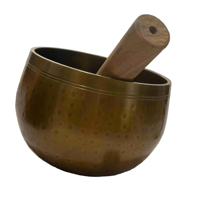 Bronze singing bowl with wooden striker on a gray background