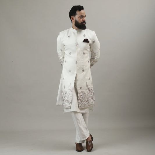 Person wearing a white embroidered outfit against a plain background