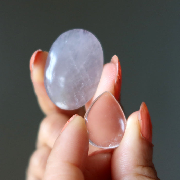 Hand holding a clear crystal against a dark background