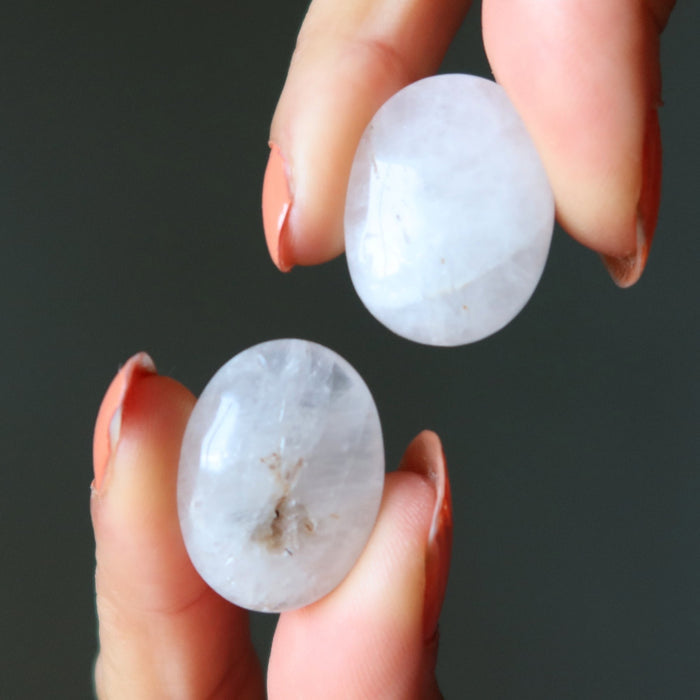 Two white stones held between fingers against a dark background