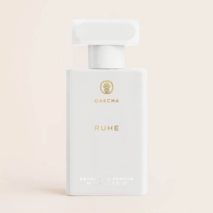 Front view of Ruhe perfume bottle showing white design, gold Oakcha branding, and 50 milliliters on beige background