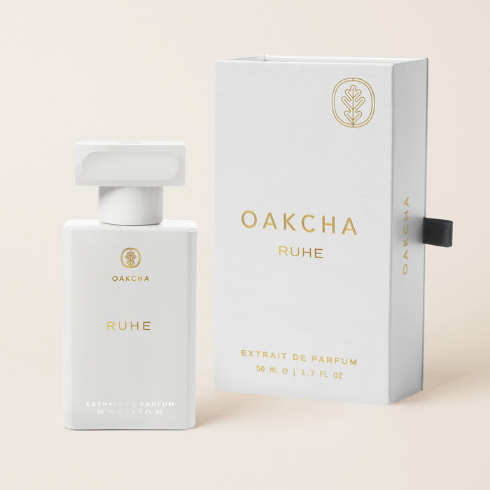 Front view of Ruhe Extrait de Parfum bottle and box showcasing white packaging and 50 mL size against a beige background