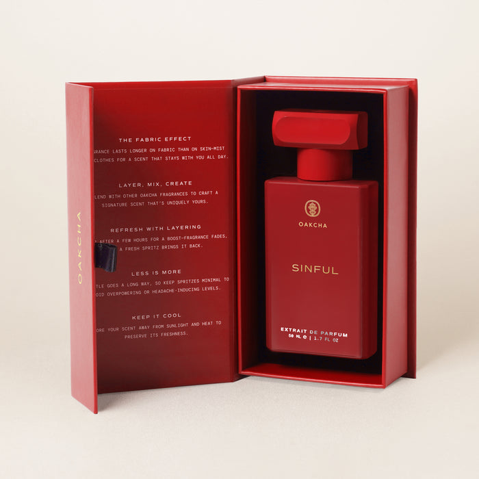 Front view of Sinful red Extrait de Parfum bottle in an open red presentation box on a light background