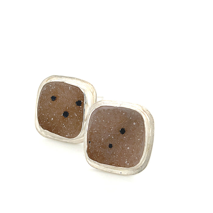 Close-up of natural quartz crystal, druzy texture, with brown inclusions, gemstone, with sterling silver cufflinks on a white background, front close up overview.