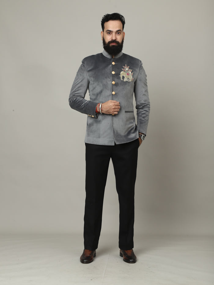 Person wearing a gray embroidered jacket and black pants on a plain background