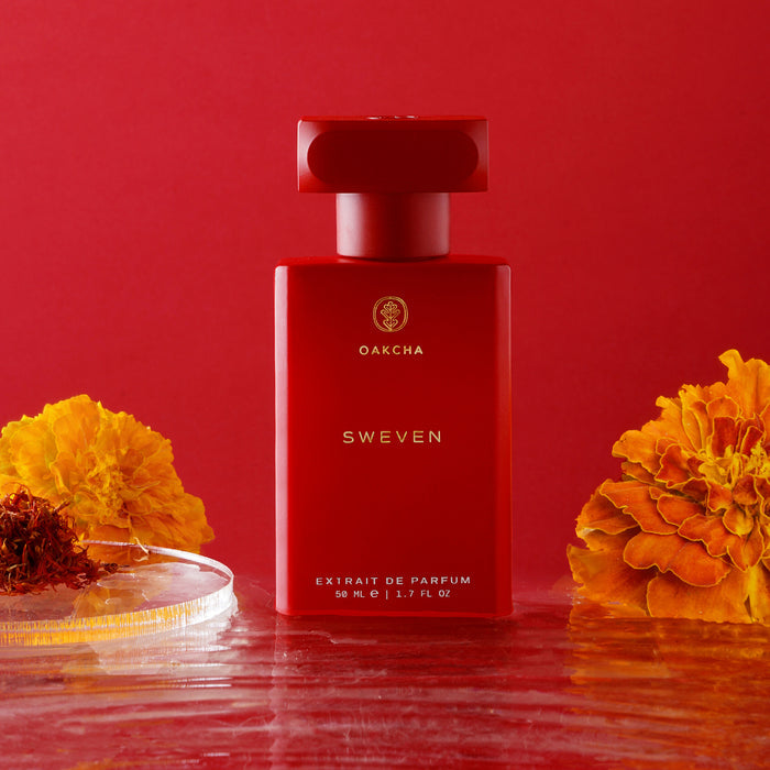 Front view of Sweven perfume bottle, matte red bottle with gold Oakcha logo and SWEVEN text on red backdrop with orange flowers