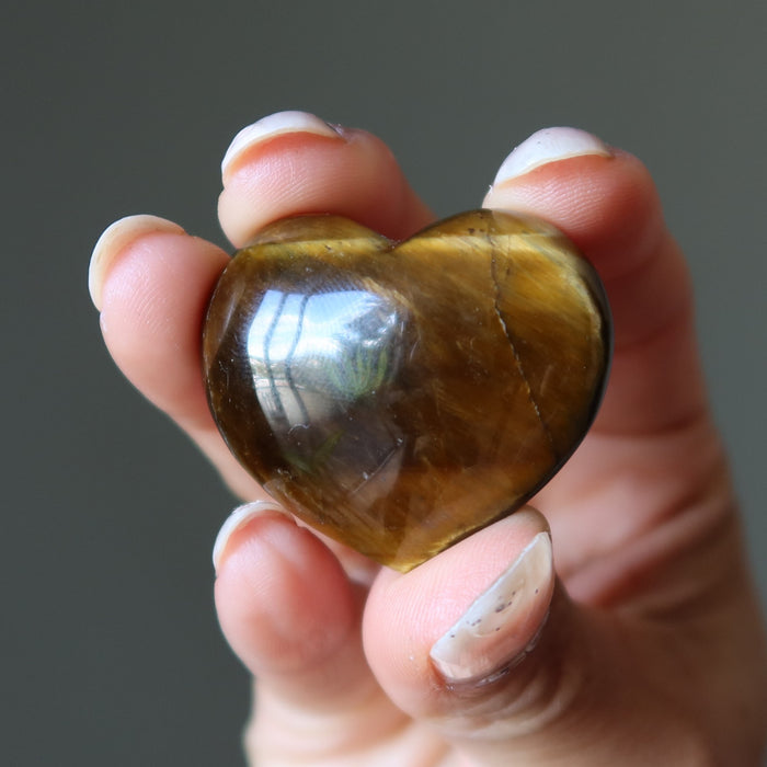 Heart-shaped brown stone held in a hand with a neutral background