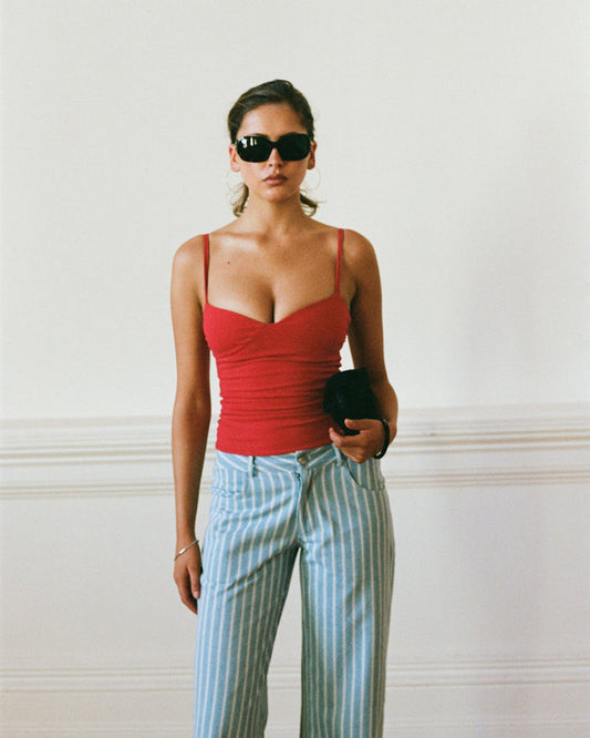 Women's singlet top in deep red colour featuring figure-hugging fit, contoured waist, and bust gathering.